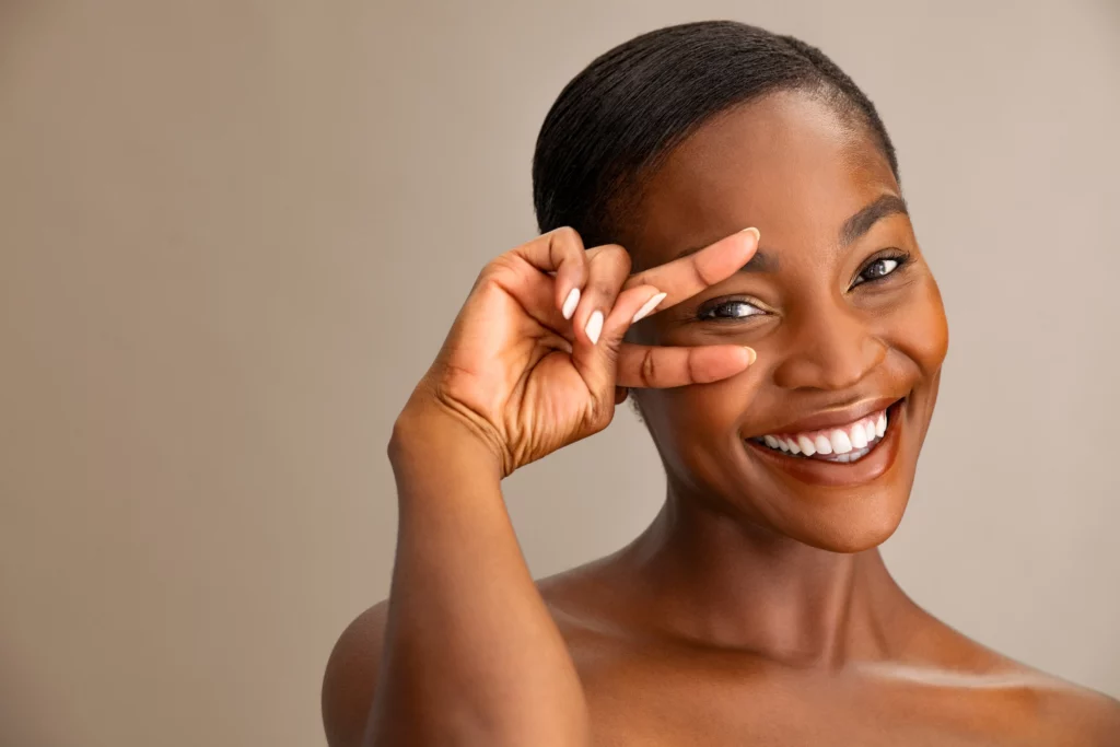 a woman smiling and holding her fingers to her eye
