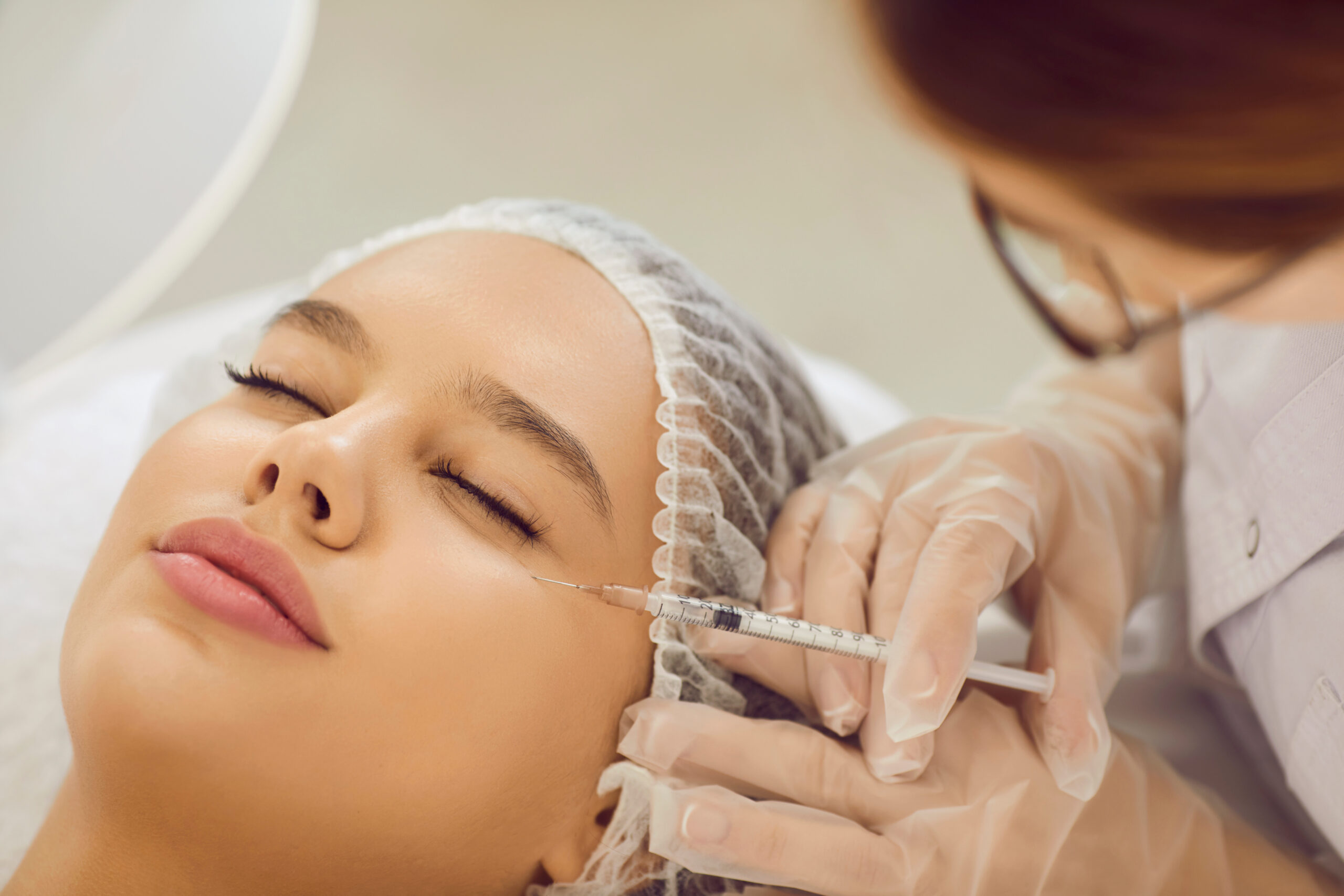 Young woman getting professional aesthetic treatment and receiving botox injection